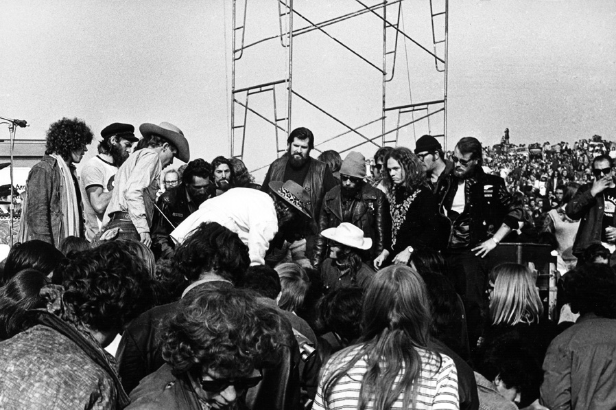 photo: Hells Angels, acting as security and hoodlums, surround Marty Balin, white hat, of the Jefferson Airplane. For a while he was knocked unconscious by The Angels at The Altamont 